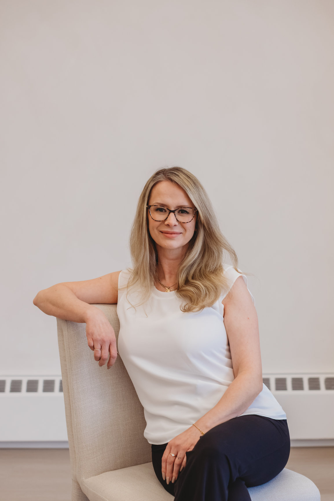 Portrait of Sarah Hope, smiling, in a cream linen chair